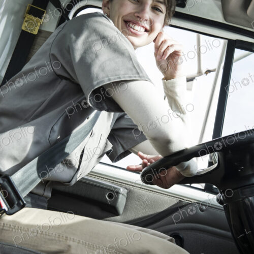 Uniformed caucasian female truck driver at the wheel of her truck Uniformed caucasian female truck driver at the wheel of her truck