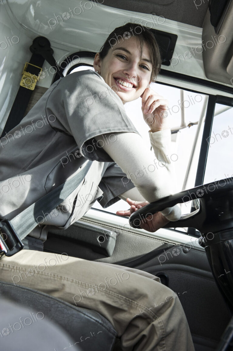 Uniformed caucasian female truck driver at the wheel of her truck