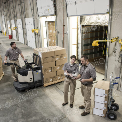 Uniformed warehouse workers loading boxed products into truck in a distribution warehosue. Uniformed warehouse workers loading boxed products into truck in a distribution warehosue.