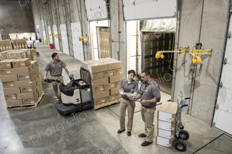 Uniformed warehouse workers loading boxed products into truck in a distribution warehosue.