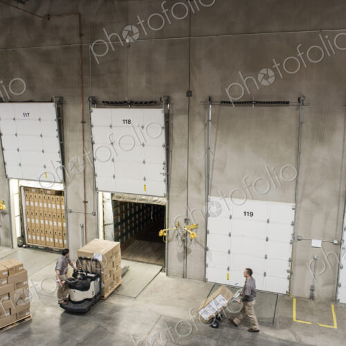 Uniformed warehouse workers loading boxed products into truck in a distribution warehosue. Uniformed warehouse workers loading boxed products into truck in a distribution warehosue.