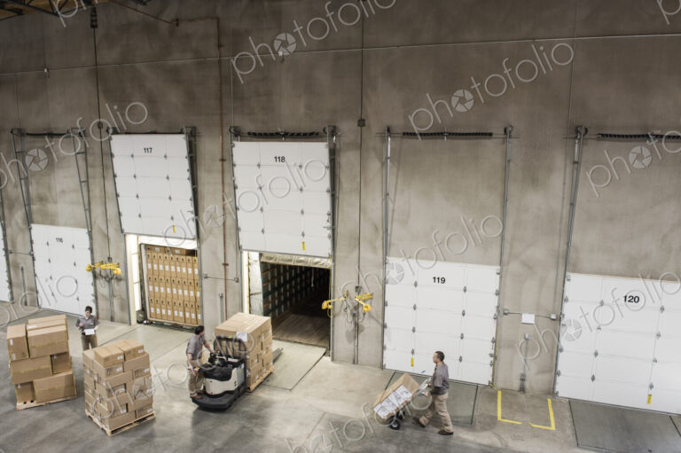 Uniformed warehouse workers loading boxed products into truck in a distribution warehosue.