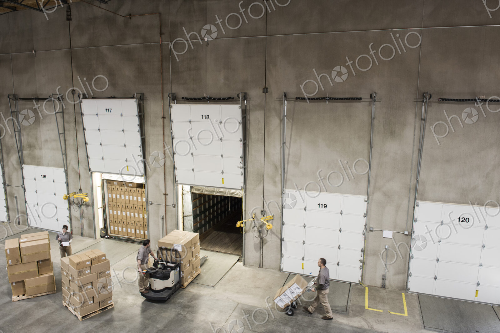 Uniformed warehouse workers loading boxed products into truck in a distribution warehosue.