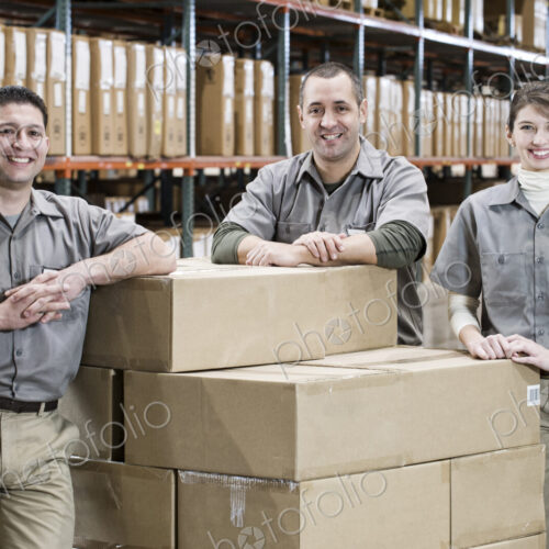 Uniformed warehouse workers surrounded by boxed products in a large distribution… Uniformed warehouse workers surrounded by boxed products in a large distribution…