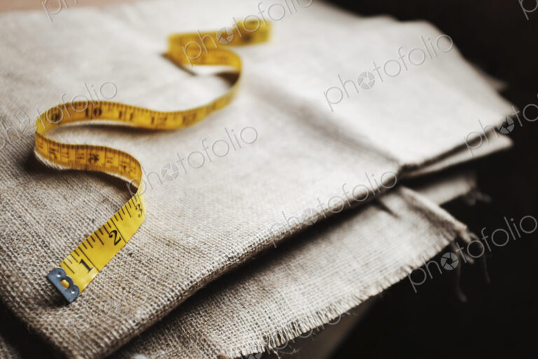 Upholstery workshop. Neutral coloured folded furnishing fabric and a yellow tape measure.