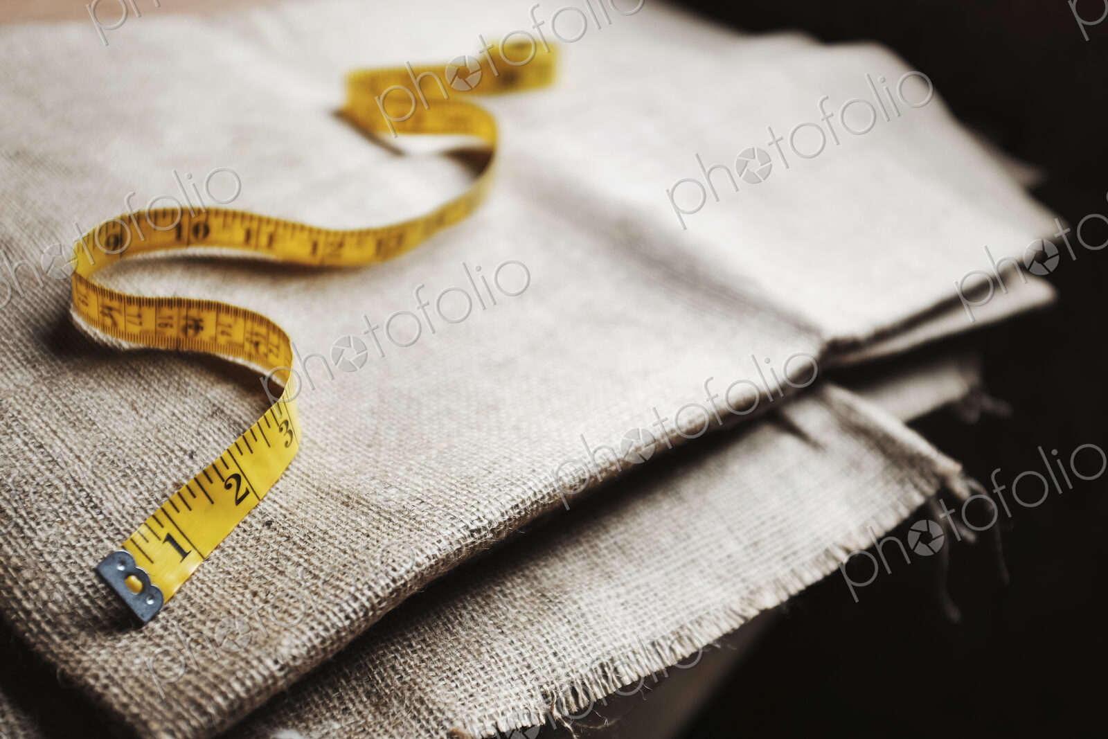 Upholstery workshop. Neutral coloured folded furnishing fabric and a yellow tape measure.