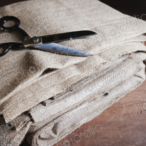Upholstery workshop. Neutral coloured folded furnishing fabric and large scissors.