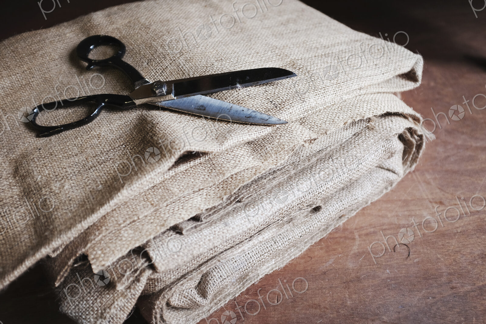 Upholstery workshop. Neutral coloured folded furnishing fabric and large scissors.