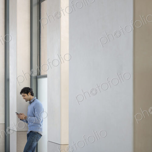 Urban Lifestyle. A man in a blue sweater using his mobile phone. An empty building. Urban Lifestyle. A man in a blue sweater using his mobile phone. An empty building.