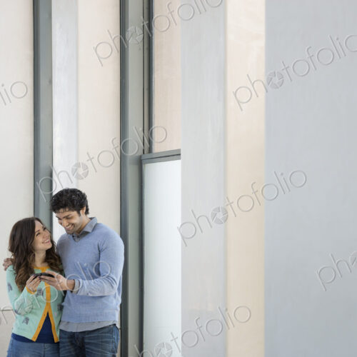 Urban Lifestyle. A young couple, man and woman side by side, looking at a mobile phone.