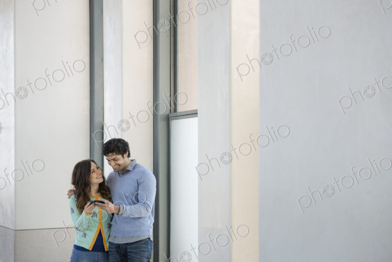 Urban Lifestyle. A young couple, man and woman side by side, looking at a mobile phone.