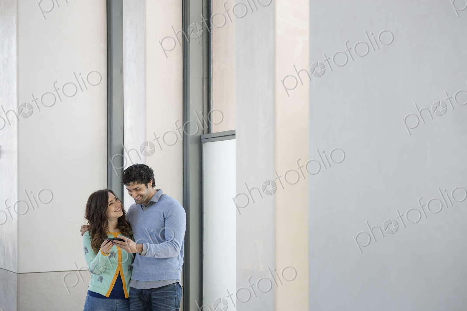 Urban Lifestyle. A young couple, man and woman side by side, looking at a mobile phone.