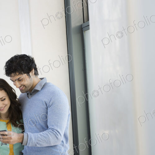 Urban Lifestyle. A young couple, man and woman side by side, looking at a mobile phone.