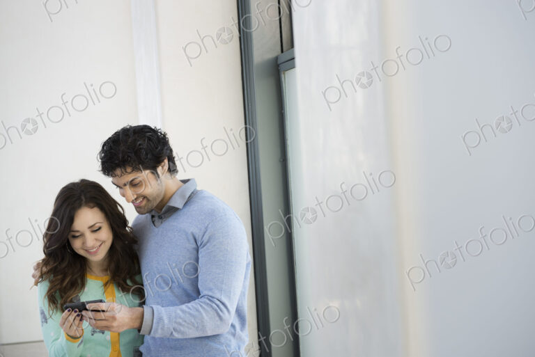 Urban Lifestyle. A young couple, man and woman side by side, looking at a mobile phone.
