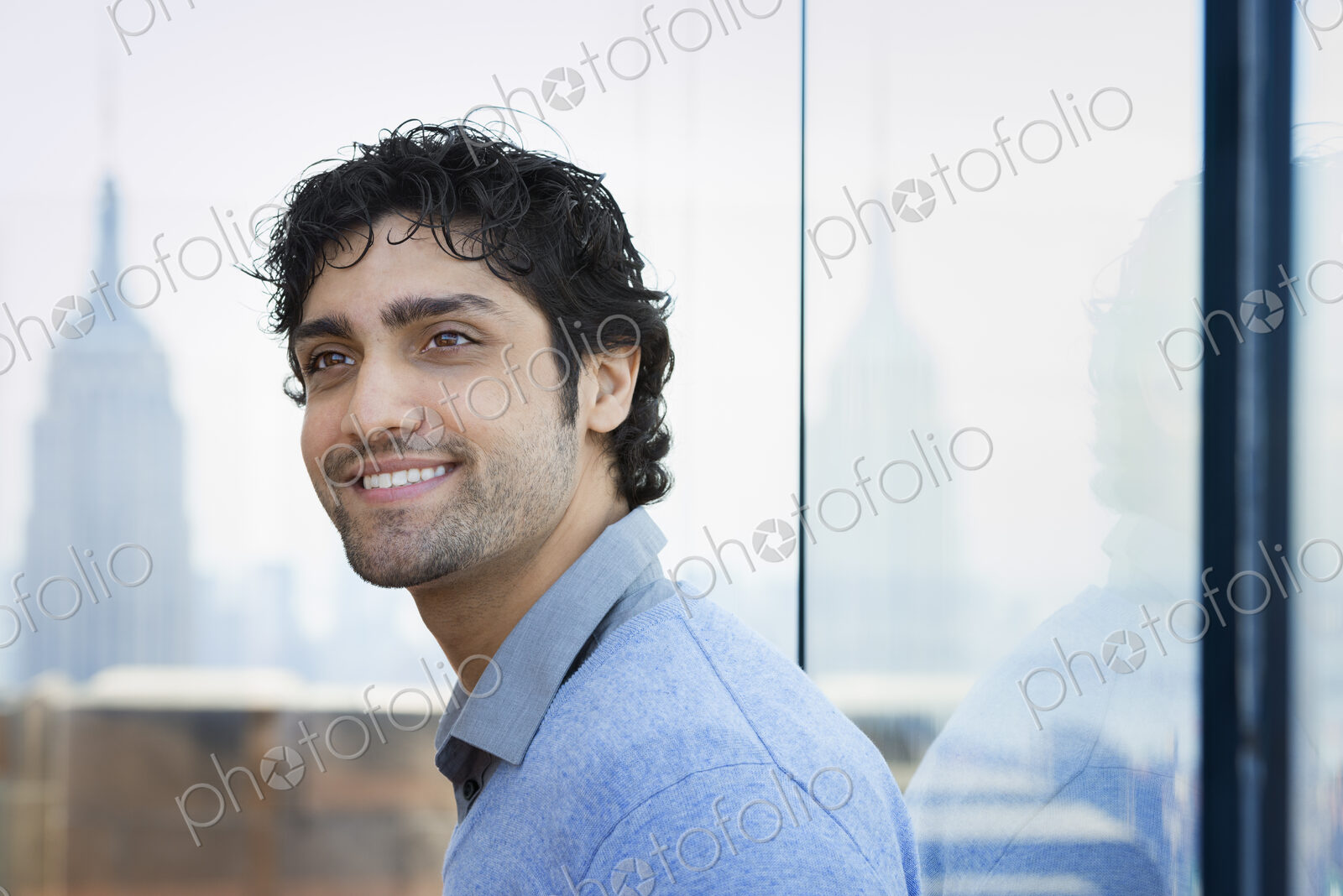 Urban Lifestyle. A young man with black curly hair wearing a blue shirt in the lobby…