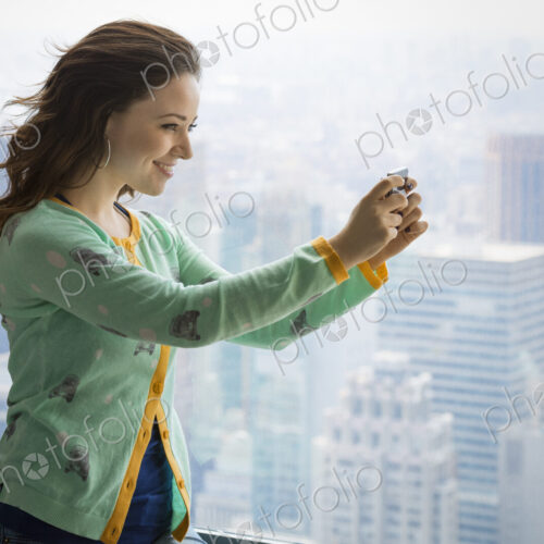Urban Lifestyle. A young woman using her camera to take a picture from an observation… Urban Lifestyle. A young woman using her camera to take a picture from an observation…