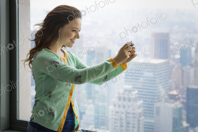 Urban Lifestyle. A young woman using her camera to take a picture from an observation…