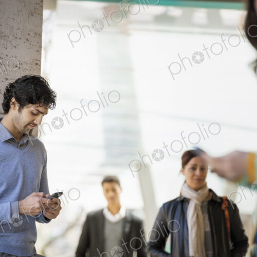 Urban Lifestyle. Three people on the sidewalk, a man and a young woman using their… Urban Lifestyle. Three people on the sidewalk, a man and a young woman using their…