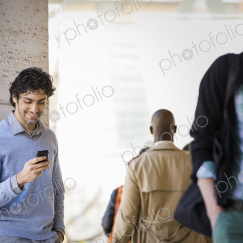 Urban Lifestyle. Three people on the sidewalk, a man using his mobile phone, a man in… Urban Lifestyle. Three people on the sidewalk, a man using his mobile phone, a man in…
