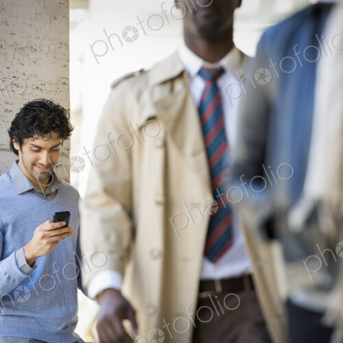 Urban Lifestyle. Three people on the sidewalk, a man using his mobile phone, a man in… Urban Lifestyle. Three people on the sidewalk, a man using his mobile phone, a man in…