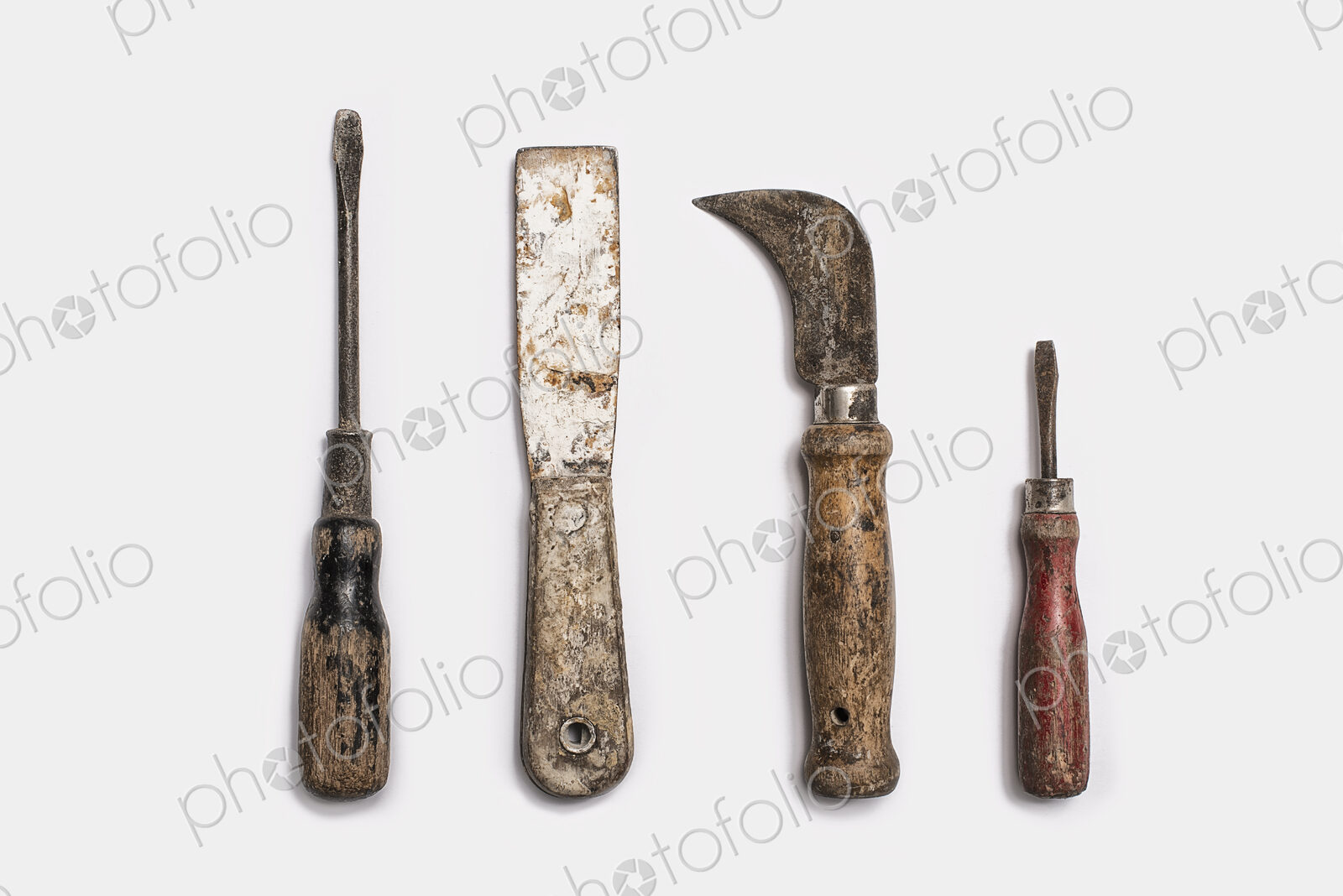 Used tools arranged in a row. Well used, worn handles, shaped wooden smooth texture.…
