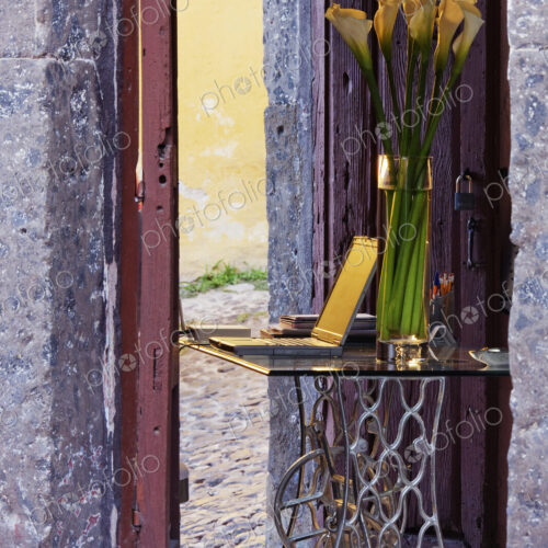 Vase and laptop on desk in old stone building. Vase and laptop on desk in old stone building.