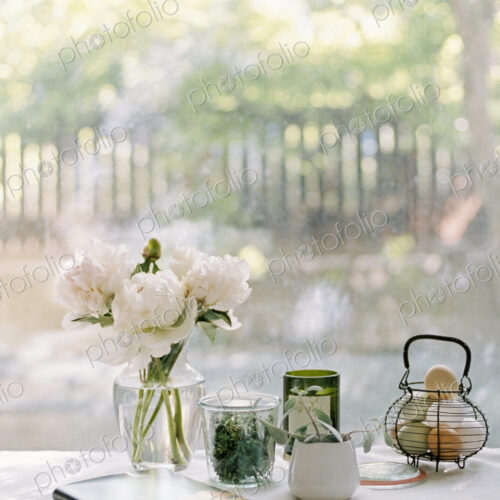 Vase with white roses, notebook and jars with herbs, and a basket of fresh eggs. Vase with white roses, notebook and jars with herbs, and a basket of fresh eggs.