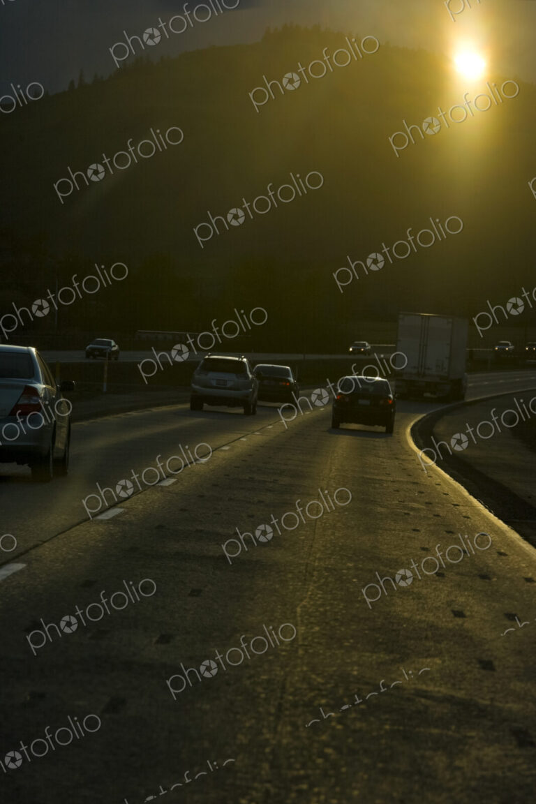 Vehicles on an interstate highway driving towards the sun.