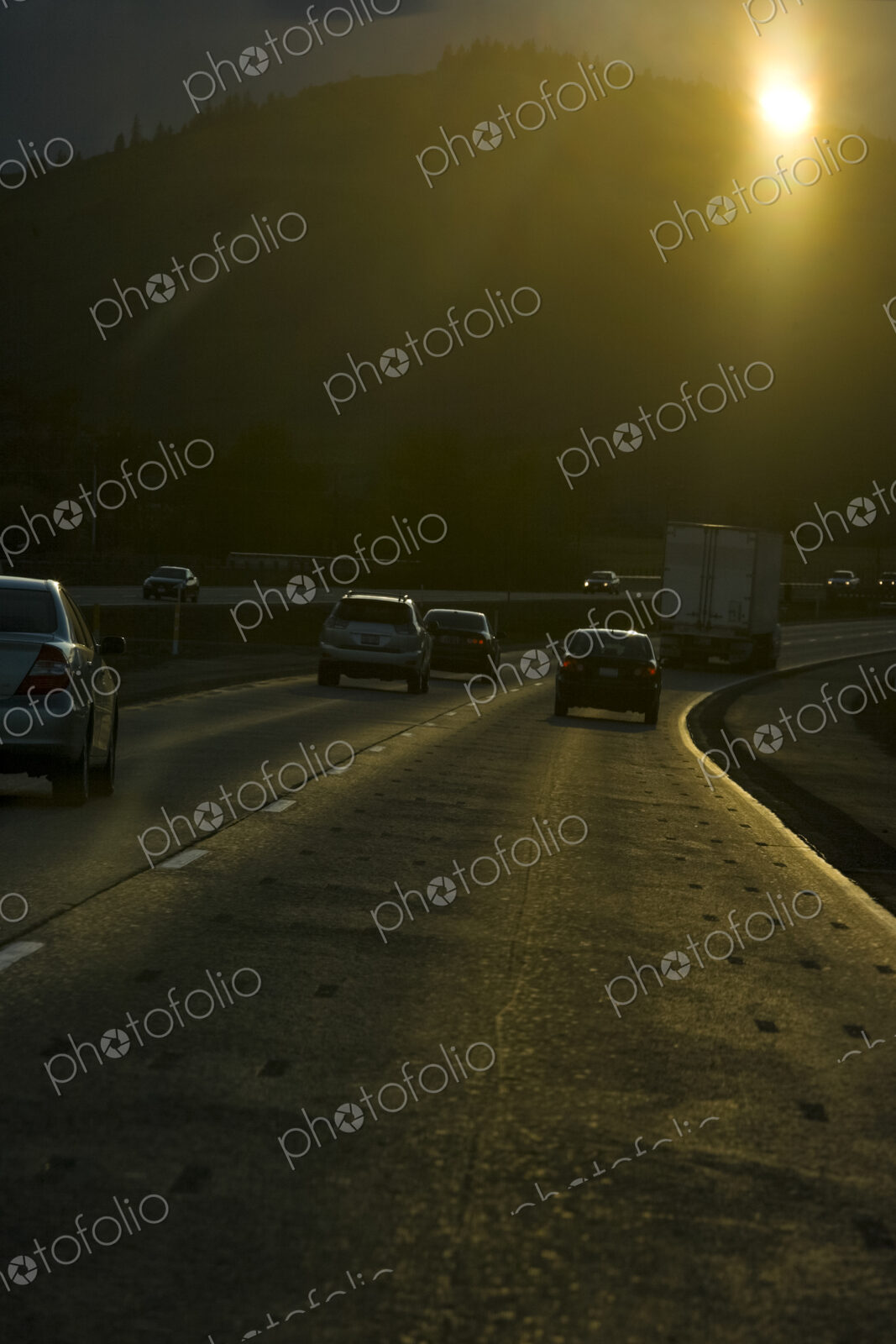 Vehicles on an interstate highway driving towards the sun.