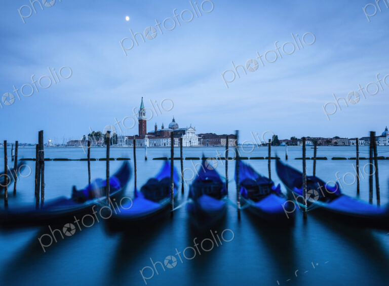 Venice lagoon, The Guideca viewed across the lagoon, gondolas moored, at night, moonlight.