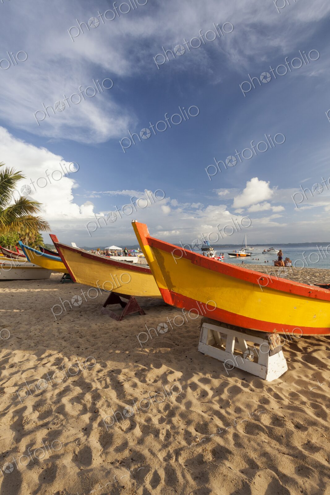 Vibrantly painted wooden fishing boats rest on the golden sand of Crash Boat Beach in…