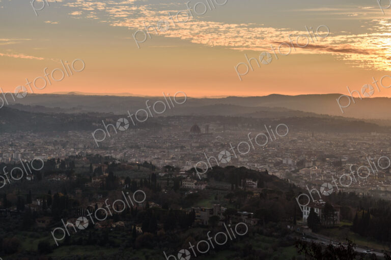 View across Florence city at sunset from above, outlines of city landmarks.
