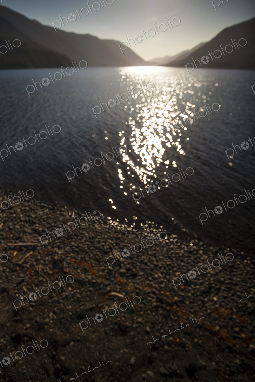 View across Lake Crescent, Olympic National Park, at dusk, reflections of sunlight…