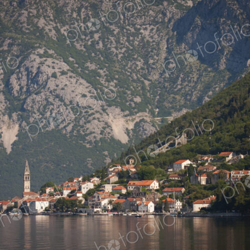 View across a lake towards a village on the slopes of a mountain in Montenegro. View across a lake towards a village on the slopes of a mountain in Montenegro.