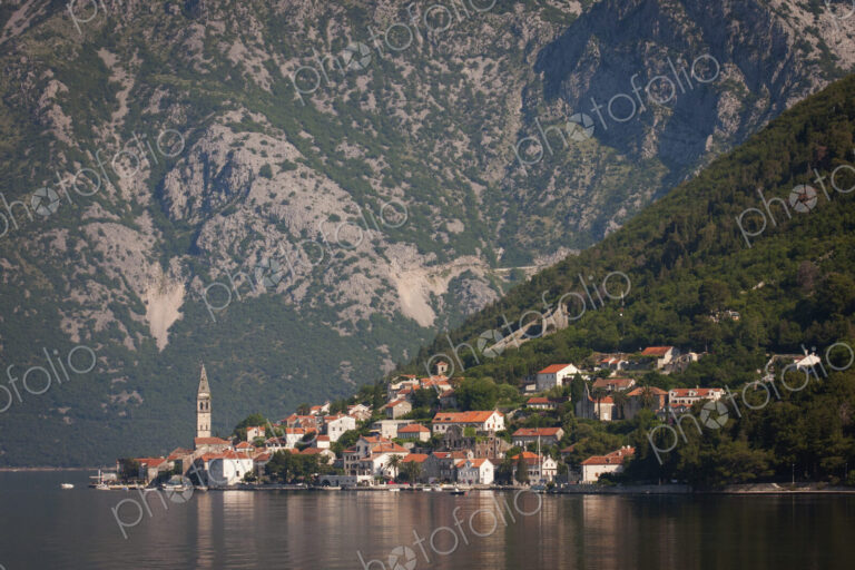 View across a lake towards a village on the slopes of a mountain in Montenegro.
