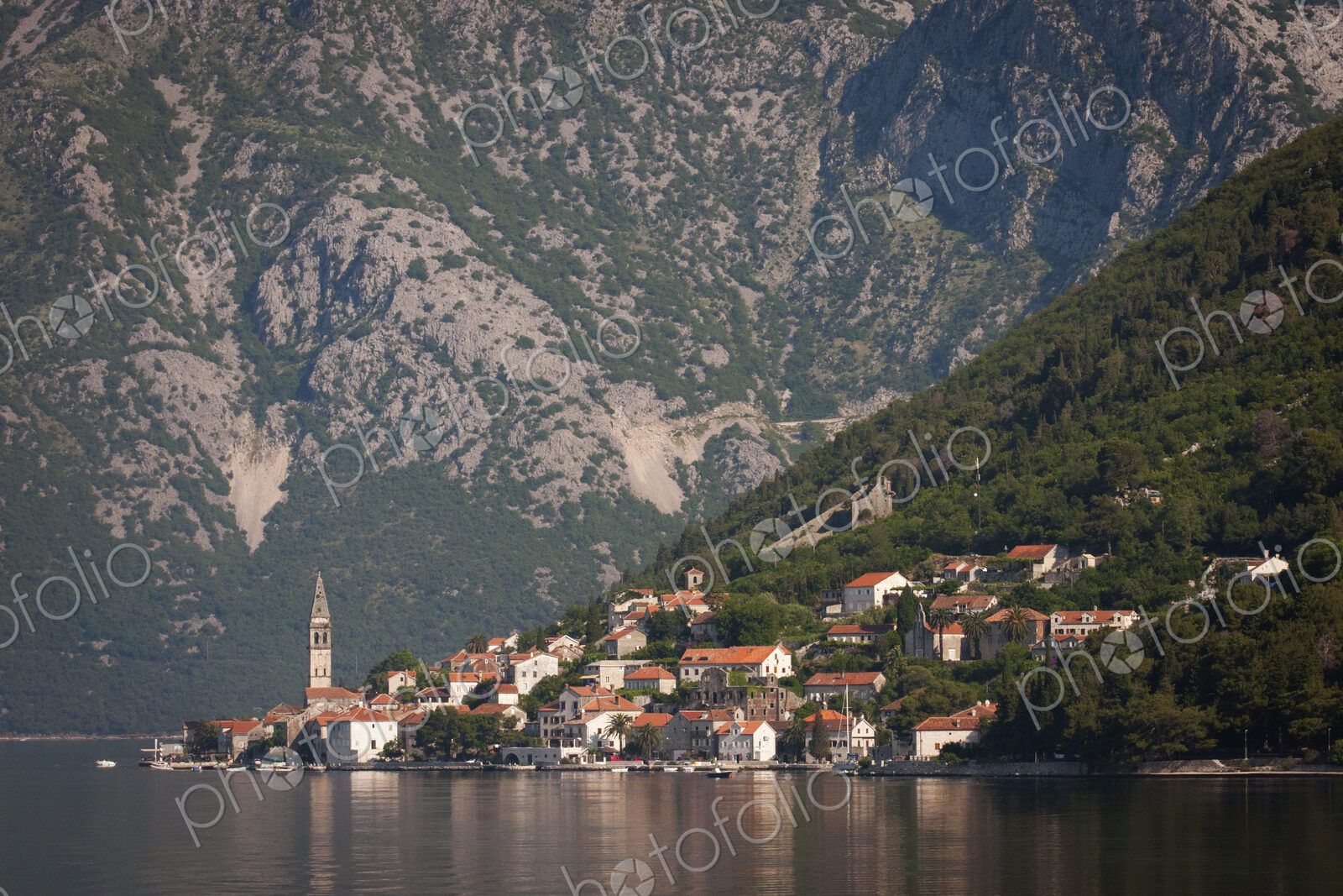 View across a lake towards a village on the slopes of a mountain in Montenegro.