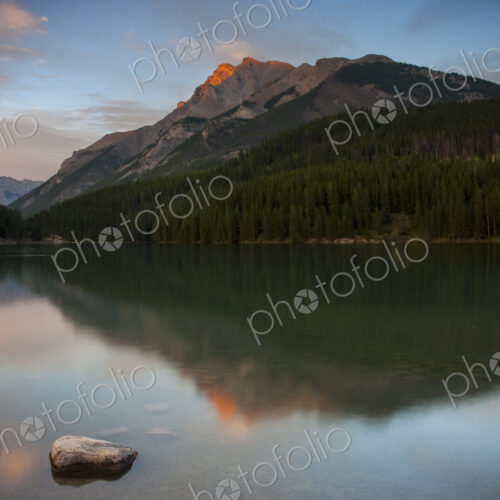 View across a lake towards the mountains in the Canadian Rockies at sunset.