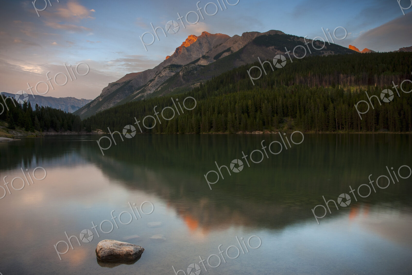 View across a lake towards the mountains in the Canadian Rockies at sunset.