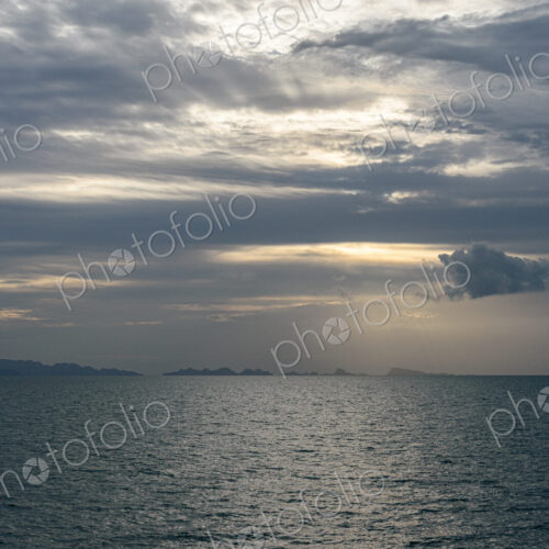 View across ocean with distant island at sunset. View across ocean with distant island at sunset.