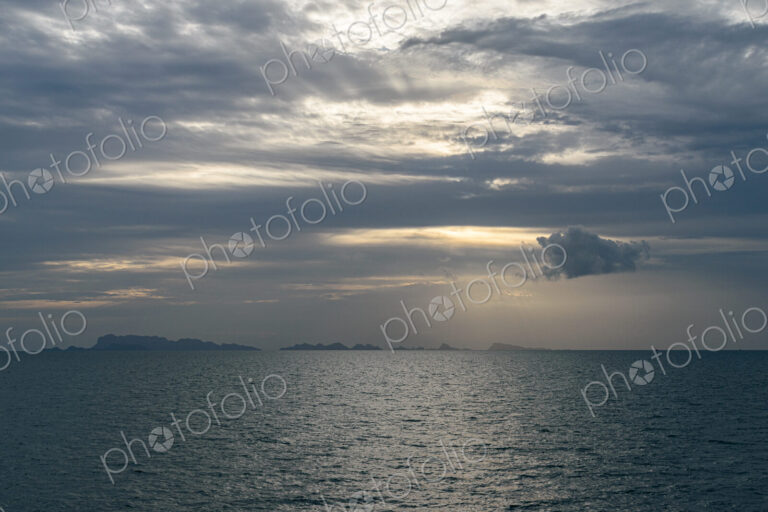 View across ocean with distant island at sunset.
