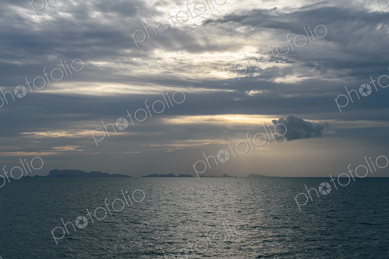 View across ocean with distant island at sunset.