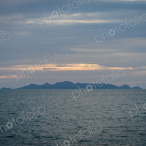 View across ocean with distant island at sunset. View across ocean with distant island at sunset.