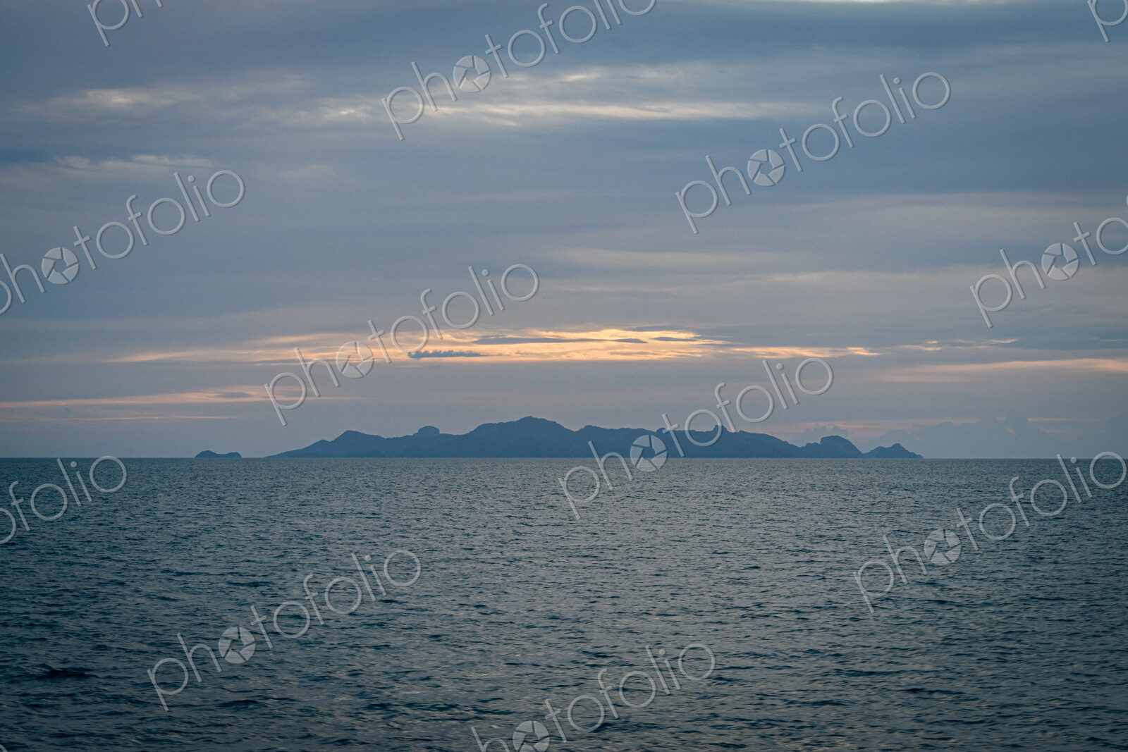 View across ocean with distant island at sunset.