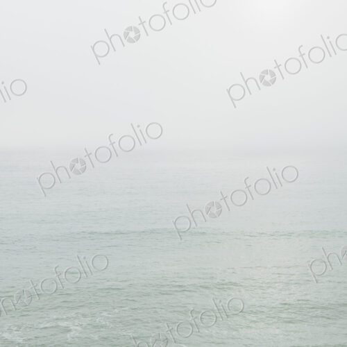 View across the ocean on a calm day, heavy fog in the air.