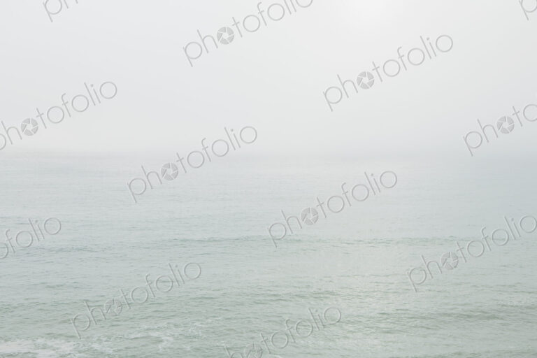 View across the ocean on a calm day, heavy fog in the air.