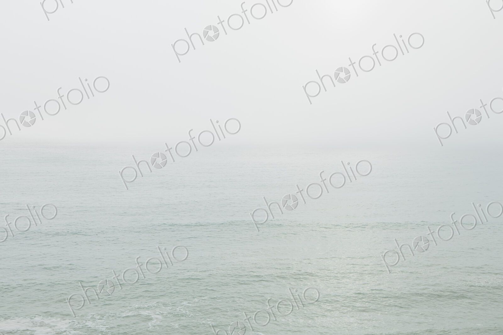 View across the ocean on a calm day, heavy fog in the air.