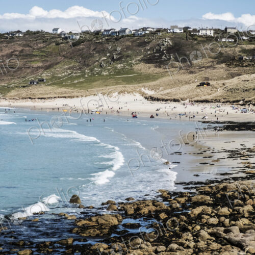 View along a coastline and sandy beach, waves breaking and people on the shore, with… View along a coastline and sandy beach, waves breaking and people on the shore, with…