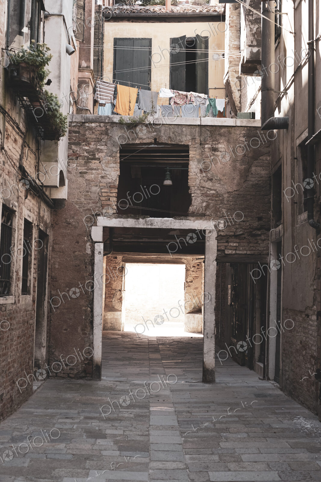 View along a narrow alley with residential buildings and gateway in Venice, Veneto, Italy.
