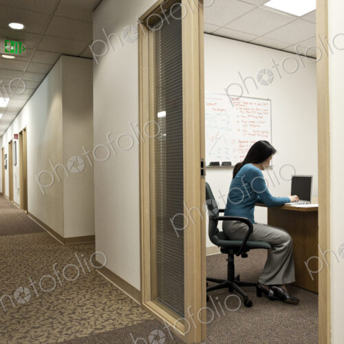 View down a hallway with an asian woman in a meeting in an office. View down a hallway with an asian woman in a meeting in an office.