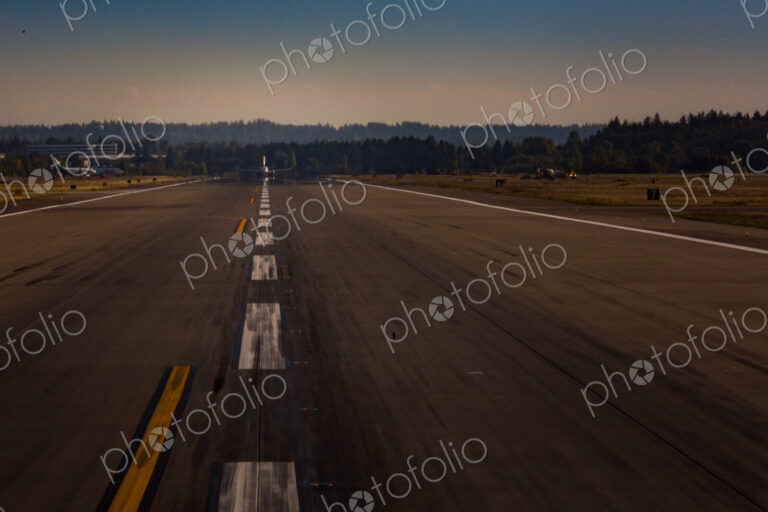 View down an airport runway, an aircraft preparing for take off.